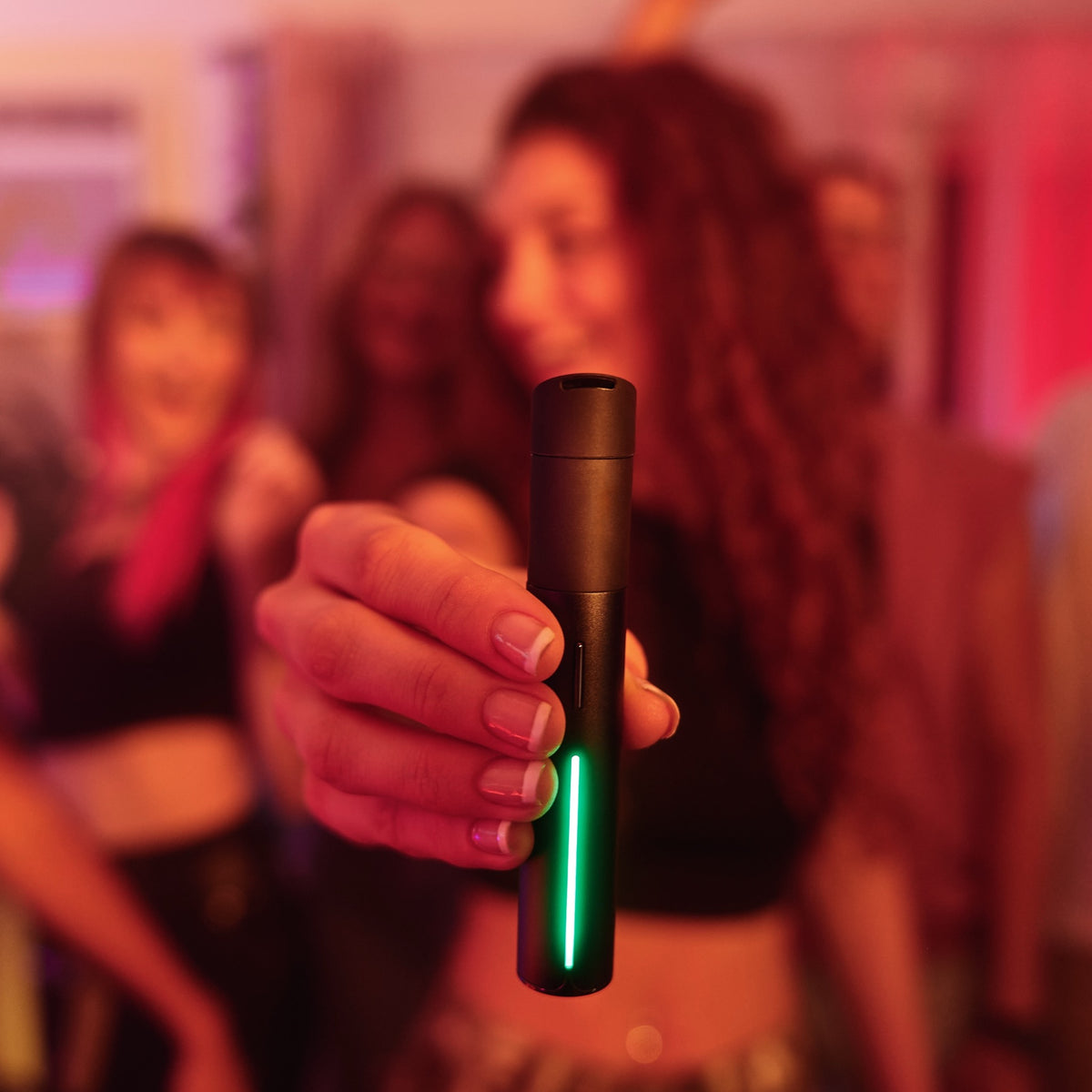 Frau hält in einer Bar den Puffco Pivot Onyx in die Kamera